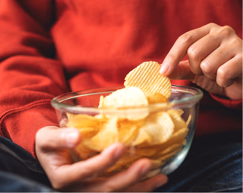 Person holding a bowl of baked potato tenis while snacking.