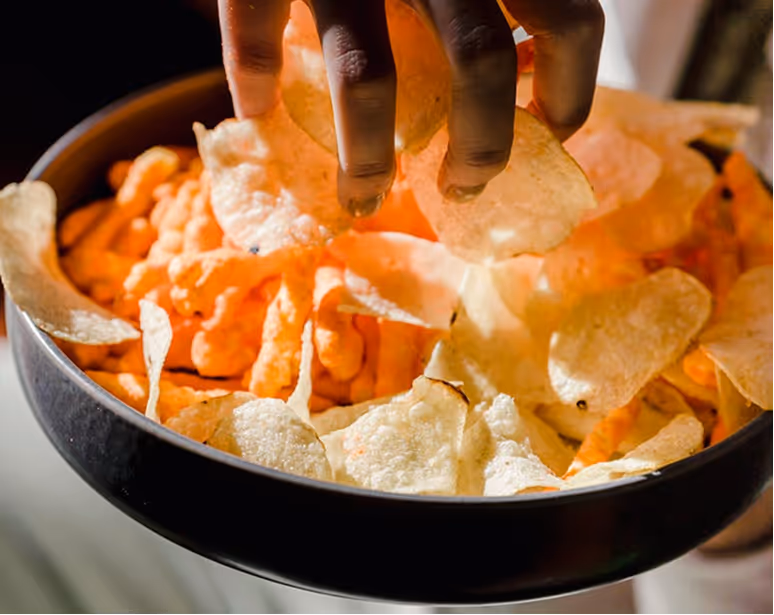 Multiple hands reaching into a bowl of baked potato tenis.